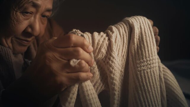 Bringing cream knit close, woman in brown sweater checking seams with wrapped-fingers at home