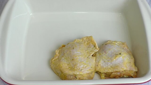 Raw chicken thighs are placed in a baking dish