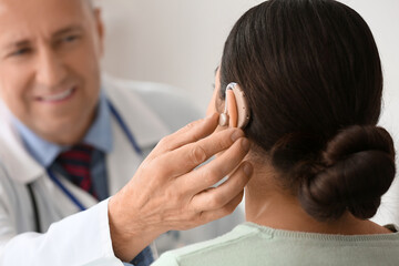 Fototapeta premium Young woman with hearing aid visiting doctor in clinic, closeup