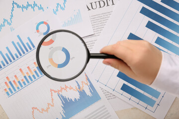 Female hand with magnifier and business charts on white background