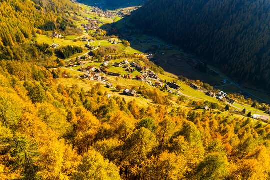 Aerial view of a valley with golden trees, houses, and a village nestled in the landscape. Rabbi valley,Stelvio National Park,Trentino,Italy