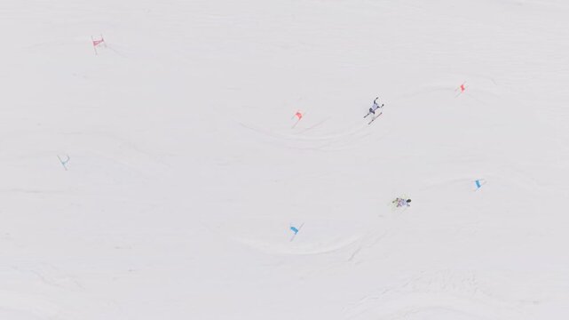 Top view drone shot of two skiers racing parallel slalom on snowy competition slope