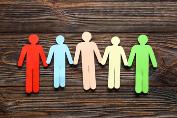 Paper human figures on wooden background