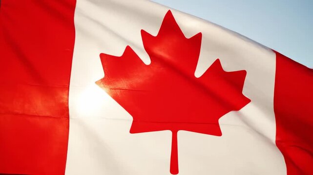 A close-up shot of the Canadian national flag, featuring the iconic red maple leaf, waving proudly against a bright blue sky with sunlight shining through the fabric.