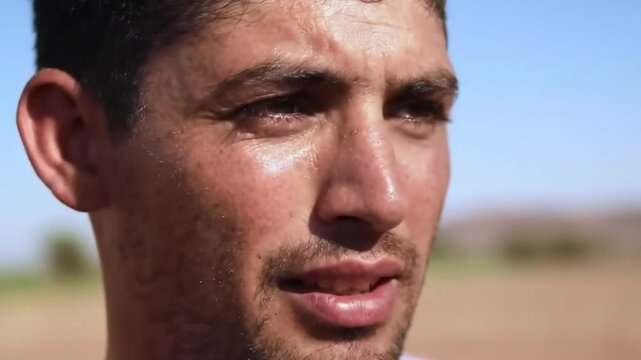 Close-up portrait of a Hispanic man with weathered skin, sweat glistening on his forehead and cheeks - close portrait weathered skin sweat interview