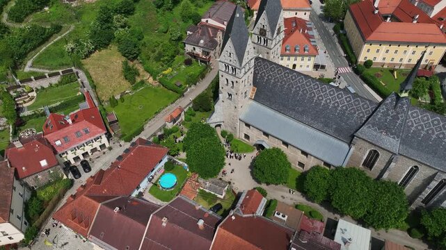 Summer drone footage showing medieval Friesach, old fortified walls, rooftops, towers, hills, serene atmosphere, warm daylight, gentle cinematic motion