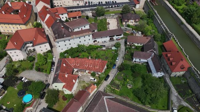 Summer drone footage showing medieval Friesach, old fortified walls, rooftops, towers, hills, serene atmosphere, warm daylight, gentle cinematic motion