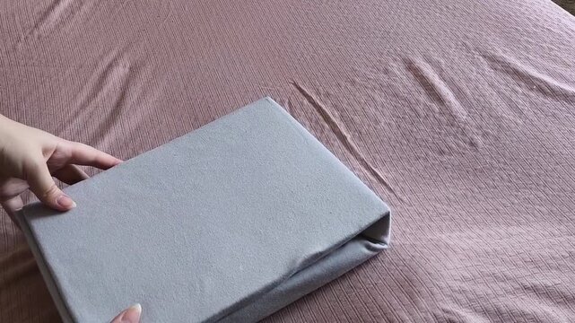 Female hands opening a pack of new bedding for the bed. Bedding. Woman unpacking sheet with elastic band