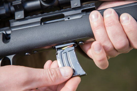 Close-up of a man loading a carbine with 22 LR cartridges