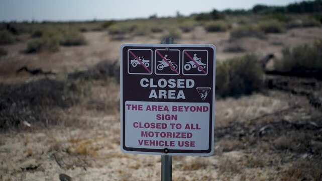 Signs at Dos Palmas Oasis inform visitors about restrictions on motorized vehicle access in the area for conservation purposes.