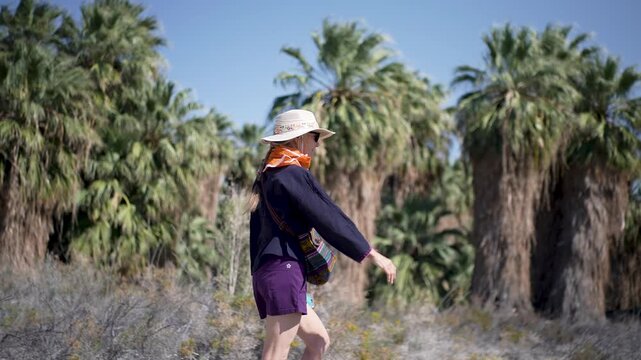 Mature woman walks along the paths of Dos Palmas oasis near Salton Sea in California taking in the sights and sounds of nature