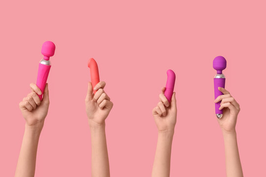 Female hands with different vibrators on pink background