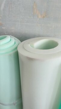 A rolled roll of white foam rubber against the background of a grunge wall. Repair, insulation of walls. Filler for upholstered furniture