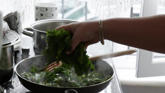 Adding Fresh Chopped Spinach to Frying Pan for Cooking