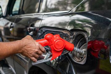 Person refueling car at gas station. Hand refueling a car with a gas pump nozzle. Person refueling...