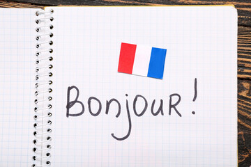 Notebook with word BONJOUR and flag of French, closeup © Pixel-Shot
