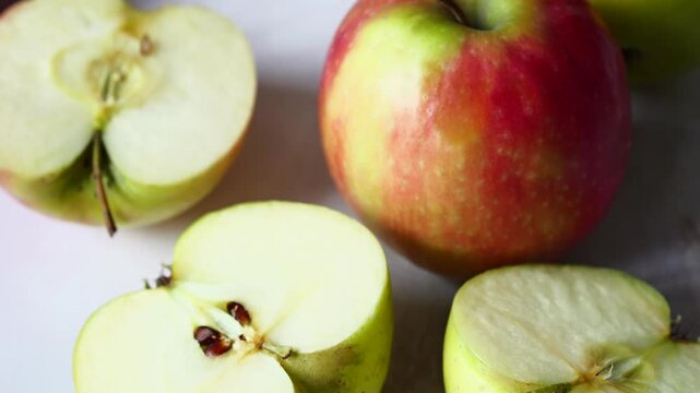 Sliced red and green apples displaying their fresh white flesh and healthy core on a light kitchen counter