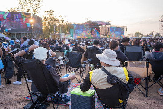 People enjoying outdoor music festival crowd watching live concert at sunset