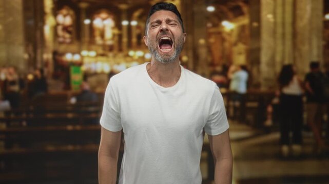 Man with mouth open shouting in catholic church interior, white t shirt and beard visible; anguish faith.