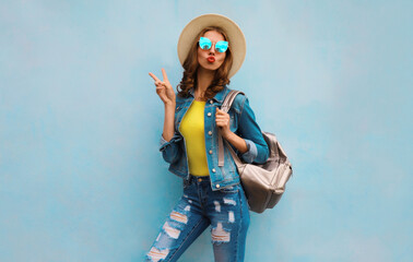 Obraz premium Stylish young woman in summer clothes with backpack posing on blue background