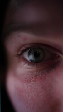 Vertical screen close up human eye lit by smartphone showing how people become increasingly addicted to social media reflecting endless scrolling digital dependence online behavior and constant attent