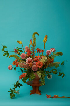 Orange and pink flower arrangement on teal background