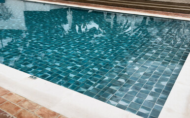 Empty swimming pool with modern design, mosaic decoration, metal handrails for safe descent into the water and clear blue water in summer. Spa complex, jacuzzi, spa pool, hydromassage