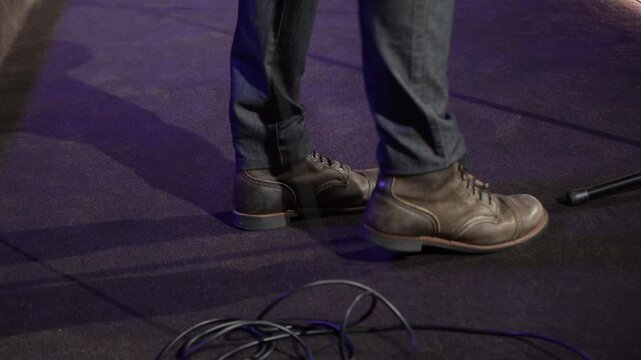 A singer and guitarist tapping his feet to the music on stage
