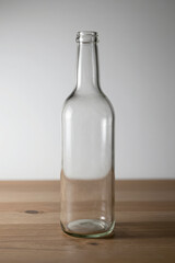 Clear Empty Glass Bottle Standing Upright on Wooden Surface with Soft Gradient Background Minimalist Product Photography for Packaging or Beverage Industry Use