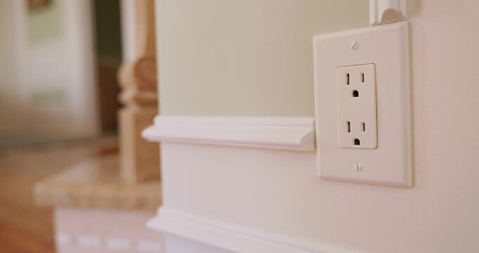 Hand inserting and removing electric plug from wall power outlet