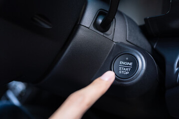 Detailed close-up of a driver's finger about to push a car's modern engine start stop button, highlighting ignition control and convenient automotive tech.