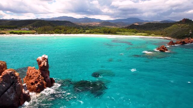 Sardinia Cea beach red rocks Faraglioni di Cea aerial side flight to turquoise sea and beach near Tortoli Italy drone 4k cinematic Ogliastra coast travel destination scenery
