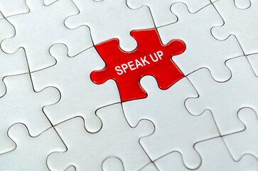 Red speak up puzzle piece placed alone in the center of a white jigsaw puzzle background.