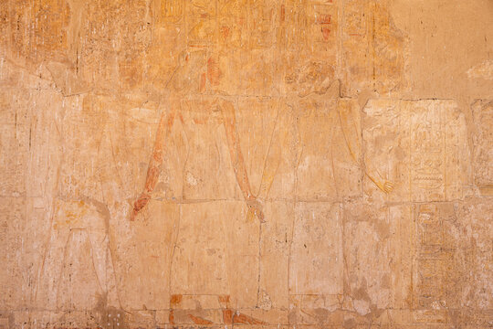 Ancient Egyptian wall relief with faint figures and hieroglyphs