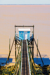 Fototapeta premium Fishing hut on stilts with wooden pier over calm estuary water