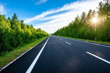 Fototapeta premium Asphalt Road Amidst Lush Forests Under Blue Sky