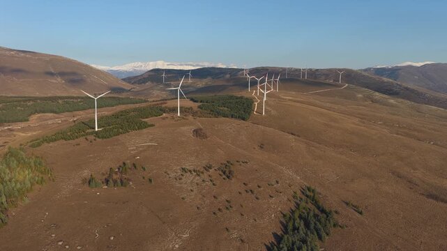 Aerial view of many wind turbines on brown mountains contrasting with the clear blue sky, generating clean energy, Cocullo, Abruzzo, Italy.