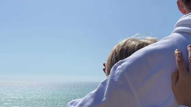 Back view of a hugging couple admiring the Mediterranean Sea from a wooden viewpoint overlooking the white cliffs of Scala dei Turchi in Sicily. Romantic intimate moment symbolizing love, connection.
