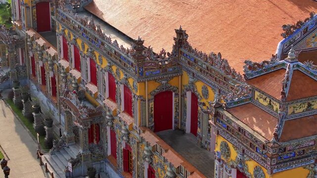 Kien Trung Palace in Hue Imperial City with a vibrant yellow facade, red shutters and roof details. Aerial Drone Shot
