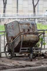 Weathered industrial hopper car abandoned on railway tracks: a rusty freight wagon with faded markings stands idle amidst overgrown vegetation. The corroded metal surface tells