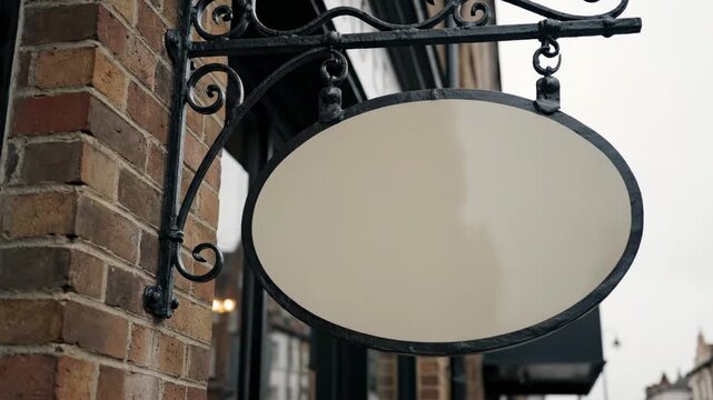 Vintage Hanging Storefront Sign concept inspired by traditional metal bracket signage, slightly aged brick exterior with a curved decorative iron arm suspending a blank oval sign in muted cream,