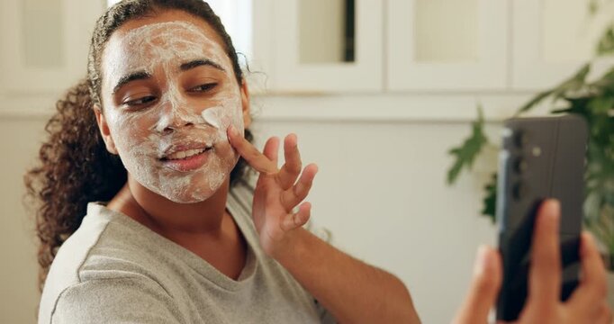 Face mask, phone and tutorial with woman in bathroom of home for cleansing or self care. Facial, skincare and streaming with influencer in apartment to apply antiaging product for wellness routine