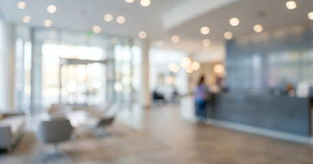 Fototapeta premium Defocused architectural interior showing reception counter, bright glass windows, and warm ambient lighting, presenting a modern corporate lobby atmosphere with smooth minimalist aesthetics.