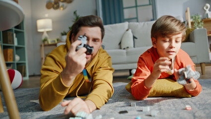 Closeup boy father playing lego photographing on toy camera lying floor room © stockbusters