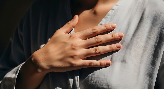 Close up view of person s hand resting gently on chest symbolizing care comfort self compassion and emotional well being during a sunny day