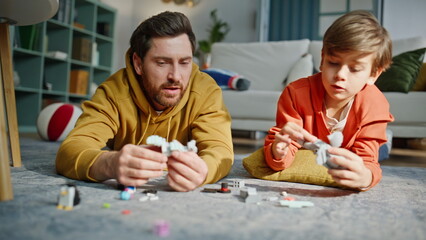 Father son building lego lying floor closeup. Smiling man little boy playing toy © stockbusters