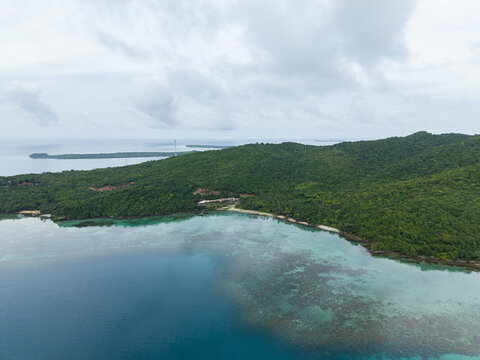 Aerial view of lush greenery embracing the shoreline where turquoise waters meet the sandy beach, Cottage Legon Waru, Karimunjawa, Central Java, Indonesia.