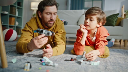 Father photographing little son holding lego on floor closeup. Playful boy home © stockbusters