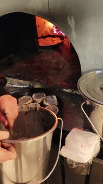 Traditional Udmurt perepechi being prepared in a wood fired oven. Burning fire in the background while mushroom filling is poured into small dough cups before baking. Authentic rustic cooking process