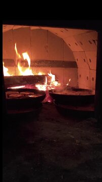 Traditional Udmurt perepechi baking inside a wood fired oven. Small open pastries with filling cooking in high heat with glowing fire and rustic oven atmosphere. Authentic traditional cuisine